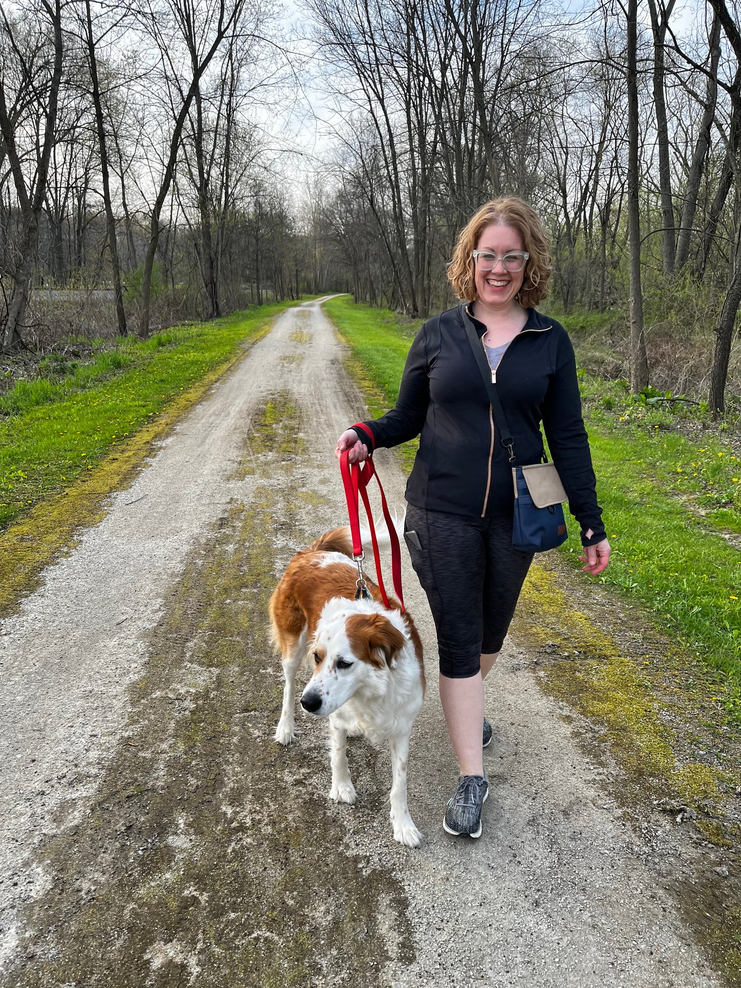 Woman wearing the WoofPack dog walking accessory bag walking on the trail with her dog.